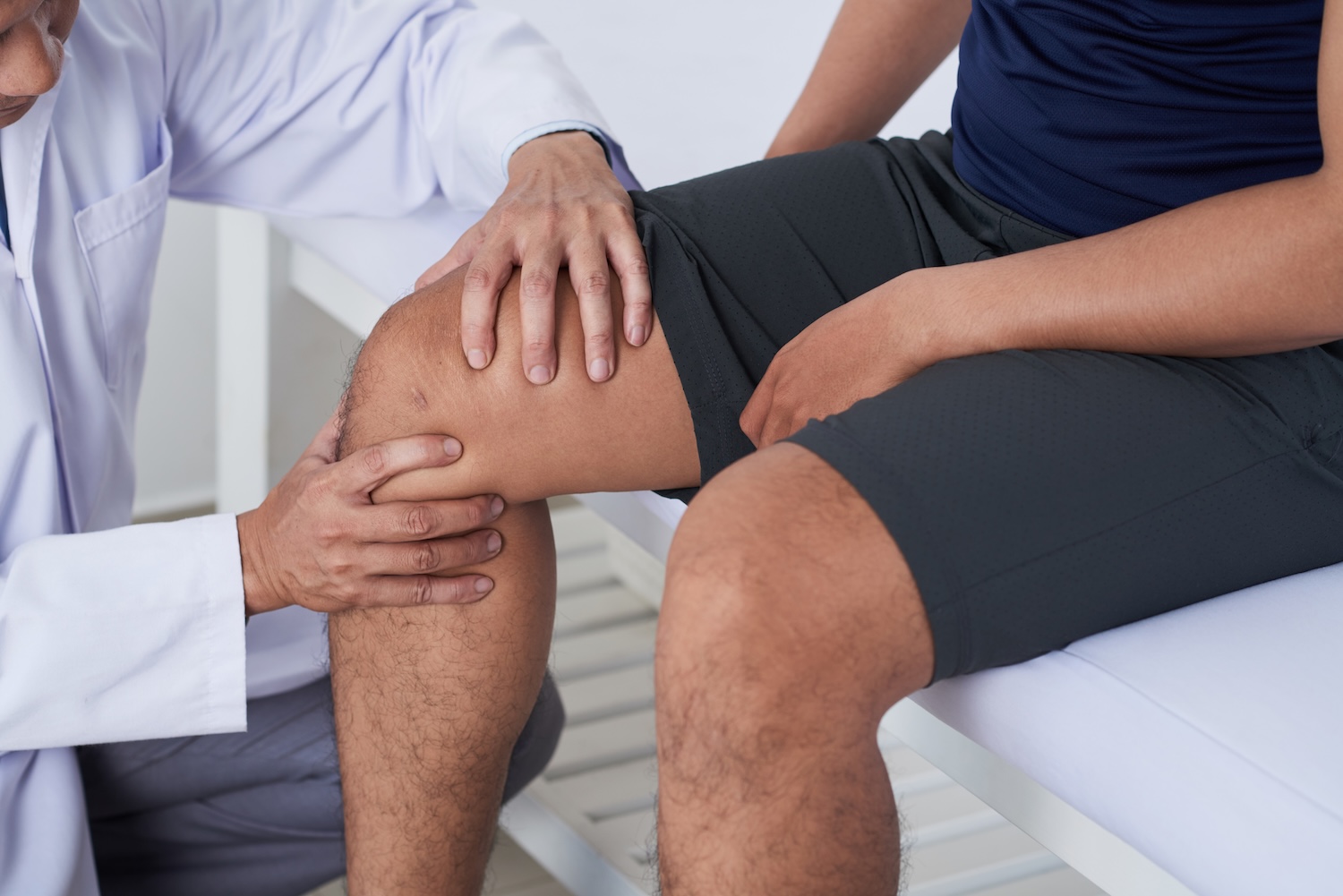 Close-up image of primary care doctor checking knee of male patient
